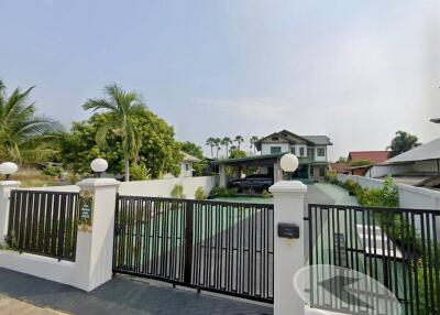 Front view of a property with a green driveway and black gated entrance