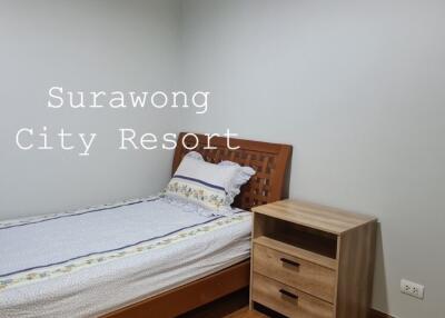 Simple bedroom with a single bed and nightstand at Surawong City Resort