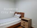 Simple bedroom with a single bed and nightstand at Surawong City Resort