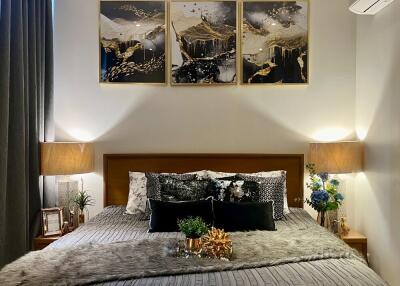 A well-decorated bedroom with a bed, nightstands, lamps, and wall art