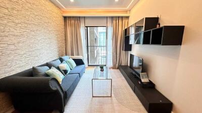 Modern living room with black sofa, wall-mounted TV, and glass coffee table