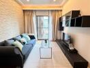 Modern living room with black sofa, wall-mounted TV, and glass coffee table