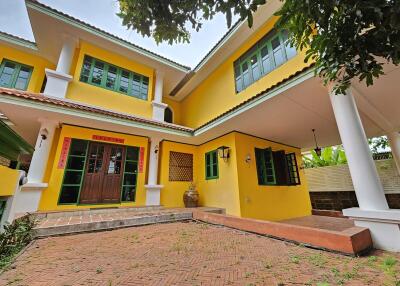 Two-story yellow house with green windows and large pillars