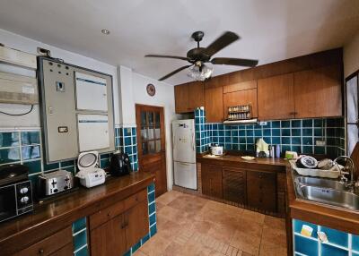 A fully equipped kitchen with wooden cabinets and green tile backsplash