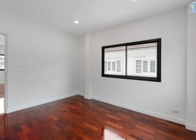 Spacious bedroom with wooden flooring and large window