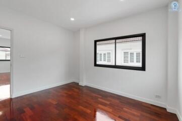 Spacious bedroom with wooden flooring and large window