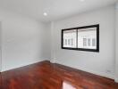 Spacious bedroom with wooden flooring and large window