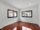 Empty room with wooden flooring and large windows