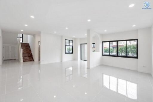 Spacious open living area with large windows and stairway