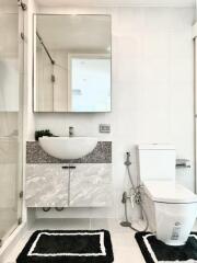 Modern bathroom with a mirror, basin, storage cabinets, toilet, and shower