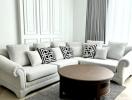 Bright living room with a light grey sofa and a round wooden coffee table