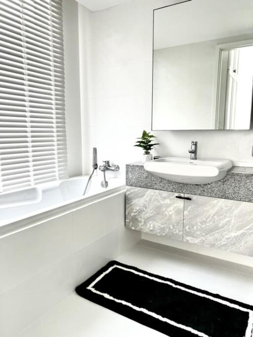 Modern bathroom with a bathtub, sink, and a large mirror