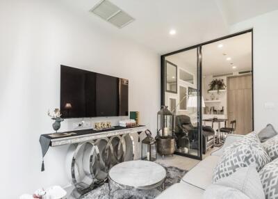 Modern living room with large TV and glass door to adjacent room