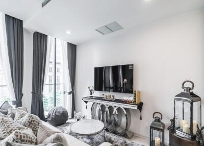 Modern living room with large windows, a flat-screen TV, and elegant decor