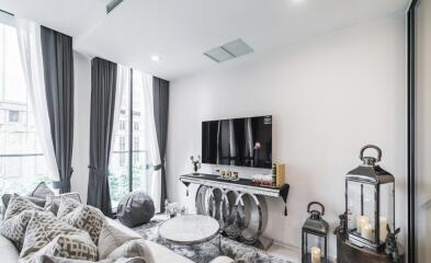 Modern living room with large windows, a flat-screen TV, and elegant decor