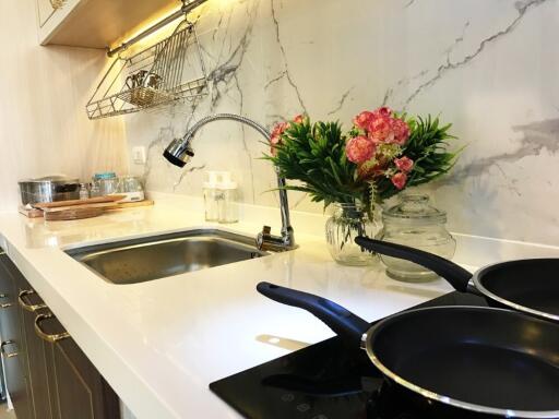 Modern kitchen with marble backsplash, built-in sink, induction cooktop, and flower decoration