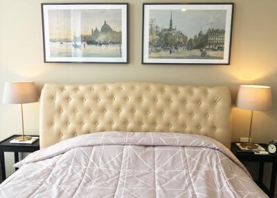 Bedroom with framed art, plush headboard, and bedside lamps