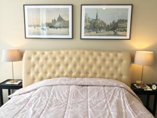 Bedroom with framed art, plush headboard, and bedside lamps