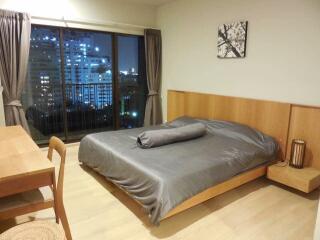 Modern bedroom with large windows and nighttime city view