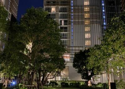 Front view of a residential building at night with greenery