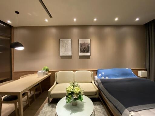 Modern bedroom with integrated living space, featuring a small dining area, a sofa, and a bed