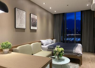 Modern bedroom with a view, featuring a bed, cozy seating area, and decorations.