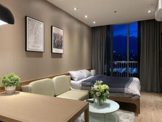 Modern bedroom with a view, featuring a bed, cozy seating area, and decorations.