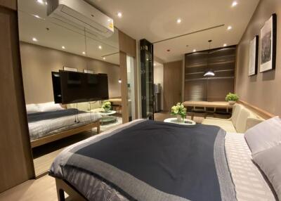 Modern bedroom with a cozy ambiance featuring a large bed, wall-mounted TV, and contemporary furnishings