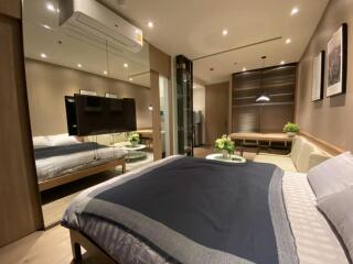 Modern bedroom with a cozy ambiance featuring a large bed, wall-mounted TV, and contemporary furnishings