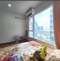 Spacious bedroom with a window view of city buildings