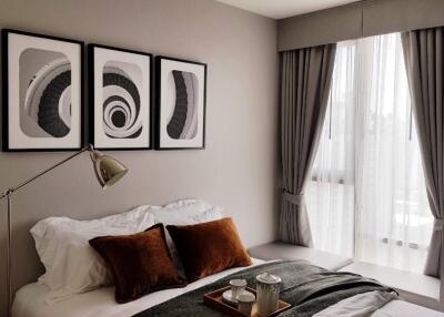 Modern bedroom with framed artwork above bed and natural light