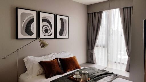 Modern bedroom with framed artwork above bed and natural light