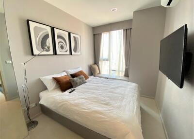 Modern bedroom with a double bed, wall art, TV, and tall window with curtains