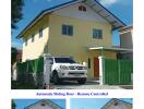 Front view of a villa with a green gate and covered parking space