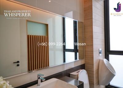 Modern bathroom with a large mirror, sink, toilet, urinal, and sleek design features