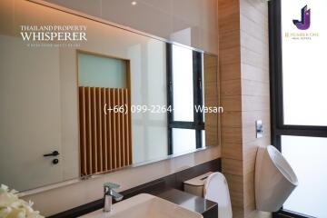 Modern bathroom with a large mirror, sink, toilet, urinal, and sleek design features