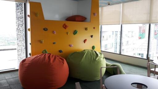 Bright recreation room with rock climbing wall and bean bag seating