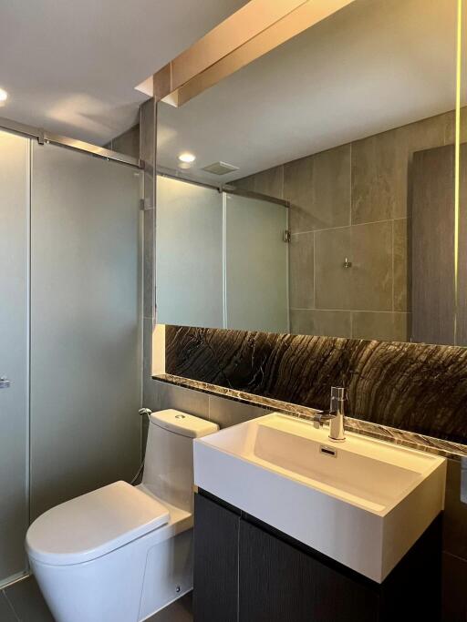 Modern bathroom with glass shower, sink and toilet