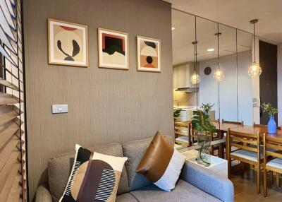 Modern living room with gray sofa, decorative pillows, artwork on the wall, and adjacent dining area