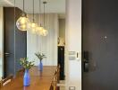 Modern dining area with wooden table, chairs, pendant lights, and decorative vases.