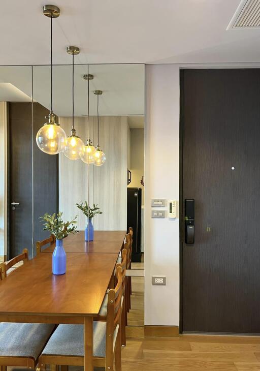 Modern dining area with wooden table, chairs, pendant lights, and decorative vases.