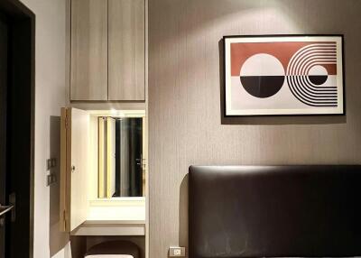 Bedroom with modern design featuring a wall-mounted art piece and vanity area