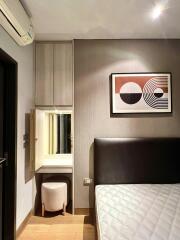 Bedroom with modern design featuring a wall-mounted art piece and vanity area