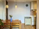 Modern kitchen and dining area with wooden dining table and chairs, hanging pendant lights, and hardwood floors