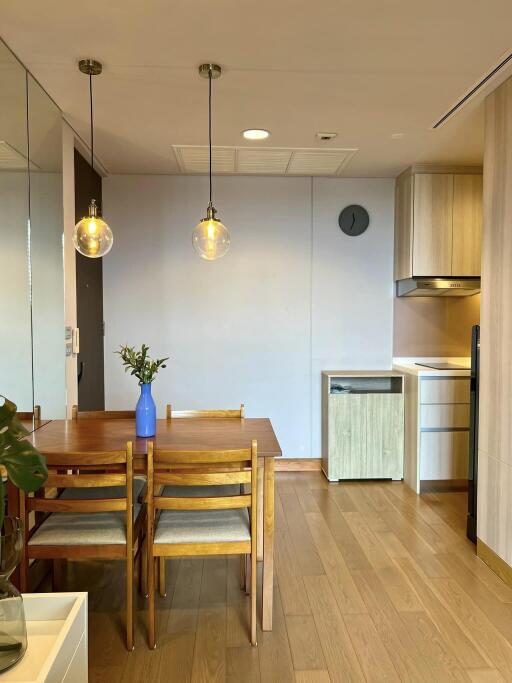 Modern kitchen and dining area with wooden dining table and chairs, hanging pendant lights, and hardwood floors