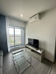 Living room with a glass coffee table and TV set near a balcony