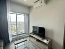 Living room with a glass coffee table and TV set near a balcony