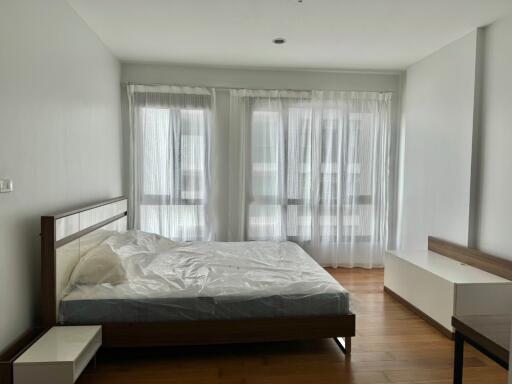 Modern bedroom with wooden flooring and large windows