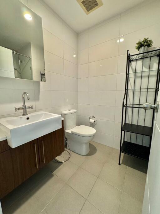 Modern bathroom with sink, toilet, and storage shelf