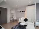 Modern living room with white furniture, wooden flooring, and wall-mounted shelves